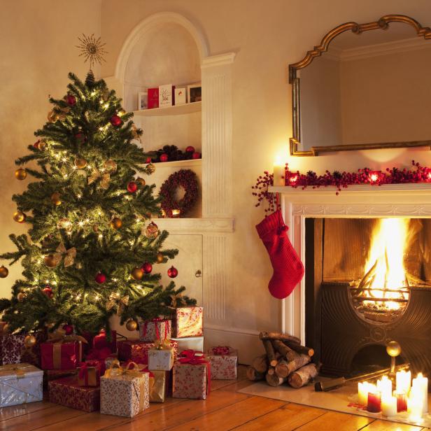 Ein festlich geschmückter Weihnachtsbaum steht neben einem Kamin mit brennendem Feuer.