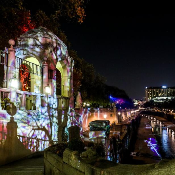 Ein beleuchteter Pavillon am Ufer eines Flusses bei Nacht.