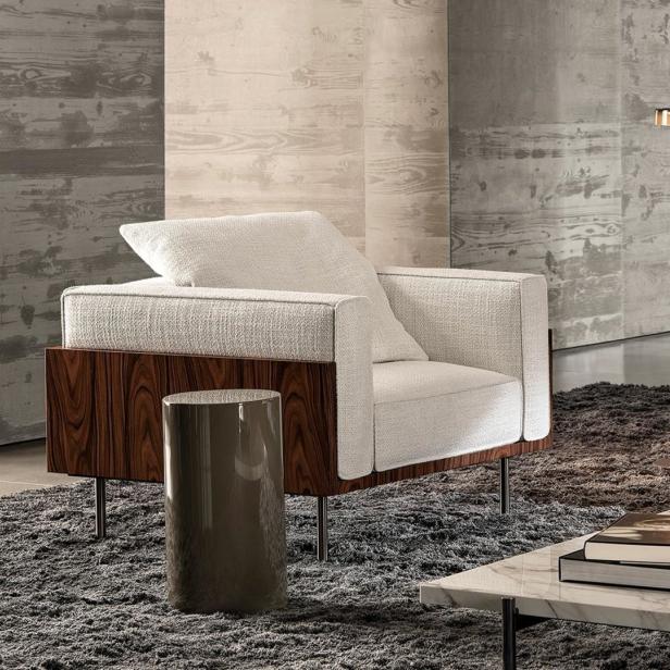 Einrichtungsszene mit einem Sessel, einem Sofa, einem Beistelltisch und einer Stehlampe auf einem Teppich.