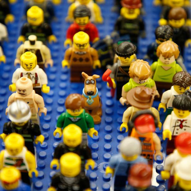 Viele verschiedene Lego-Figuren stehen auf einer blauen Lego-Platte.