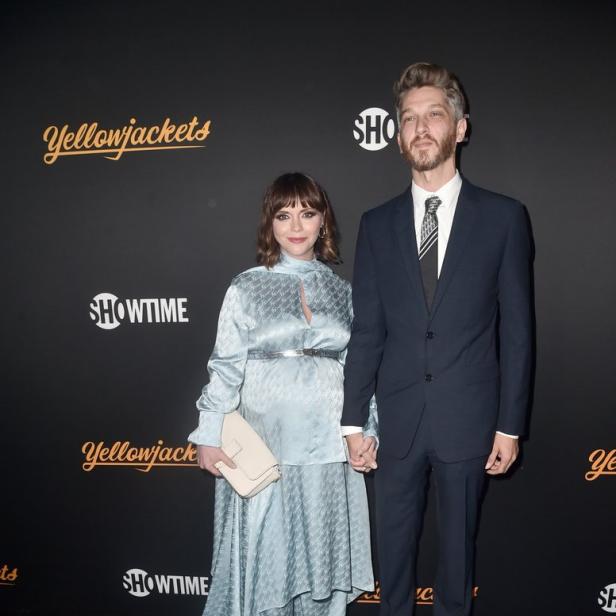 Christina Ricci und ein Mann posieren auf dem roten Teppich für „Yellowjackets“.