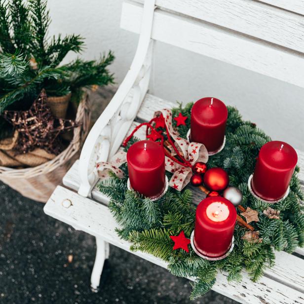 Ein Adventskranz mit vier roten Kerzen auf einer weißen Bank.