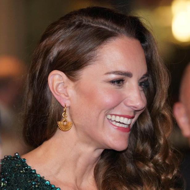 Kate Middleton lächelt und trägt goldene Ohrringe.