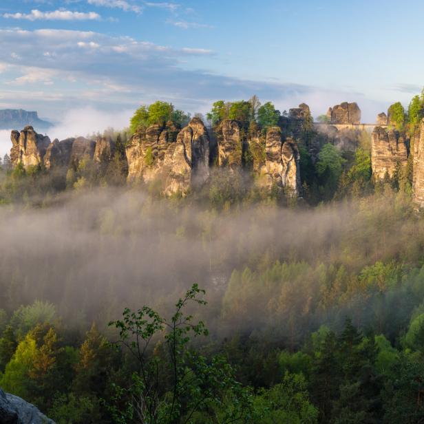 Die Felsen der Bastei ragen im Elbsandsteingebirge aus dem Nebel auf.