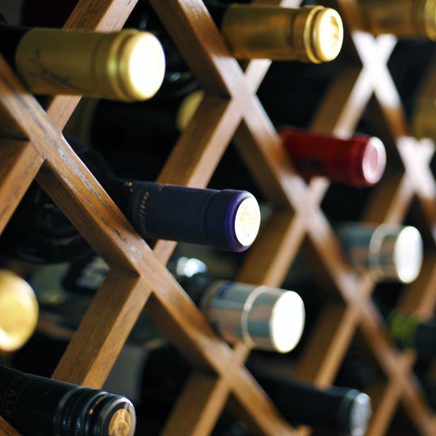 Mehrere Weinflaschen liegen in einem hölzernen Weinregal.