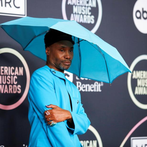 Billy Porter posiert mit einem blauen Regenschirm auf dem roten Teppich der American Music Awards.