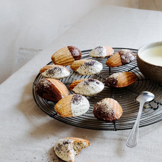 Madeleines mit Schokoladen- und Zuckerguss auf einem Kuchengitter.
