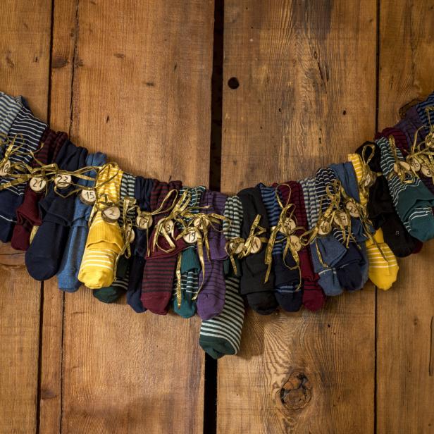Ein Adventskalender aus vielen bunten Socken hängt an einer Holztür.