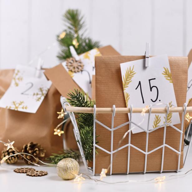 Ein Adventskalender mit kleinen Geschenken in einer weißen Drahtschale.
