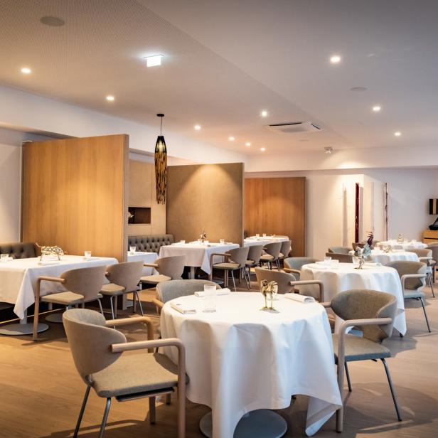 Ein elegantes Restaurant mit weiß gedeckten Tischen und hellen Holzdetails.