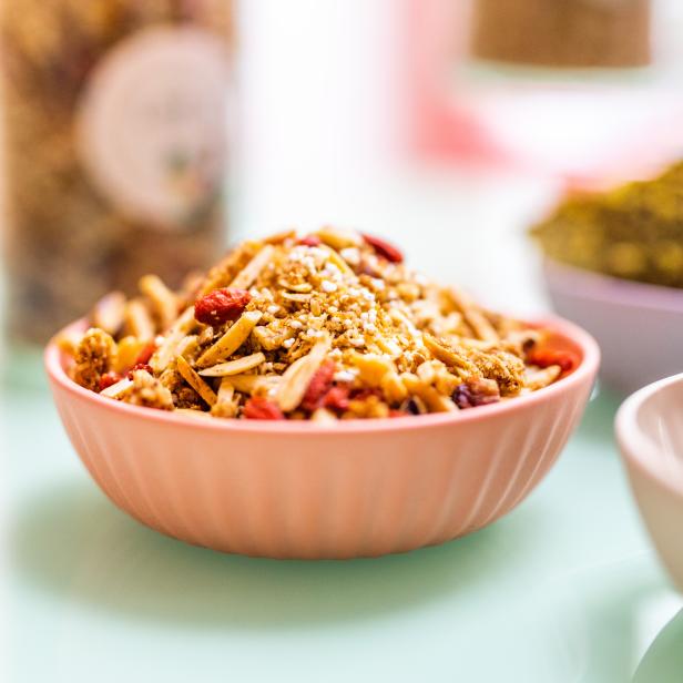 Eine rosa Schale ist mit Müsli, Mandeln und Goji-Beeren gefüllt.