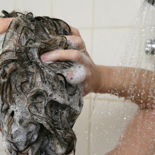 Eine Person wäscht sich die Haare unter der Dusche.
