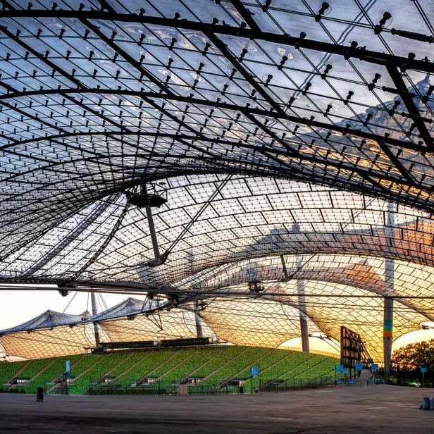 Das Olympiastadion München mit seiner markanten Zeltdachkonstruktion im Abendlicht.