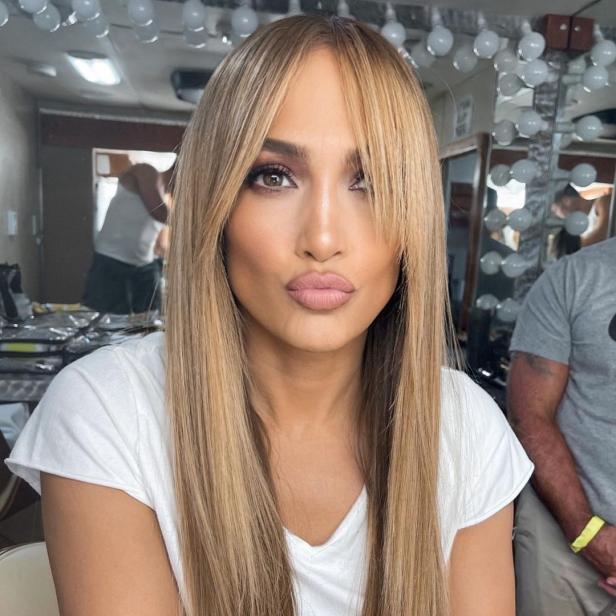 Jennifer Lopez posiert mit blonden Haaren und Pony für ein Foto.
