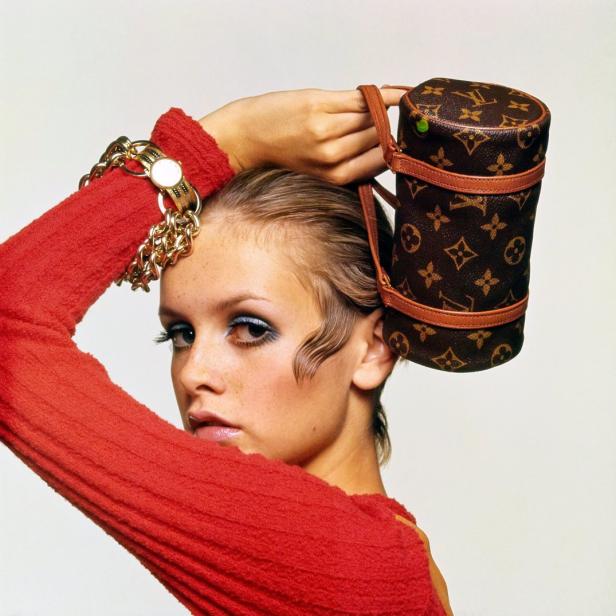 Twiggy posiert mit einer zylinderförmigen Louis Vuitton Handtasche auf dem Kopf.