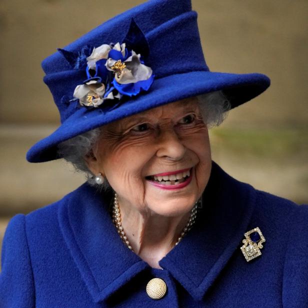 Königin Elisabeth II. lächelt in einem blauen Hut und Mantel.