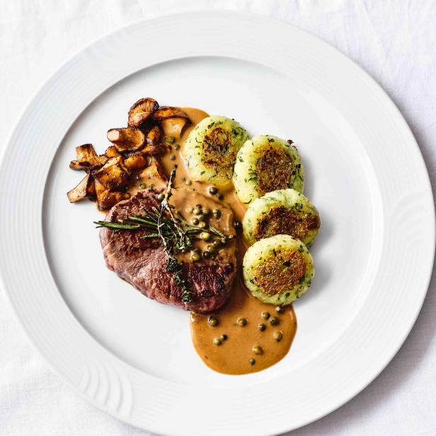 Ein Teller mit einem Steak, Spätzle, Pilzen und einer cremigen Sauce.