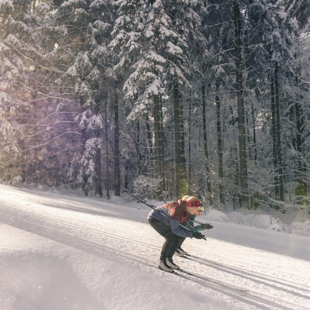 Zwei Personen beim Skilanglauf in einer verschneiten Winterlandschaft.