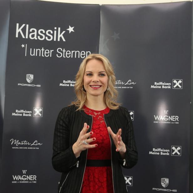 Eine Frau in einem roten Kleid posiert vor einem Banner für „Klassik unter Sternen“.