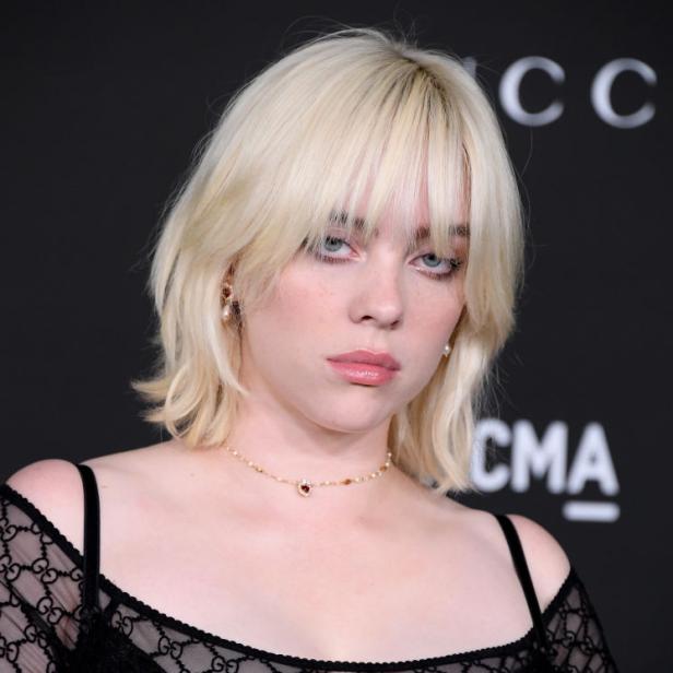 Billie Eilish mit blonden Haaren und einem schwarzen Gucci-Oberteil.