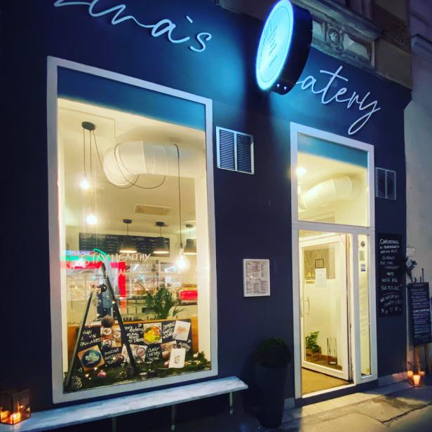 Die Fassade von „Zina's Eatery“ mit einem Schaufenster und einer einladenden Beleuchtung.