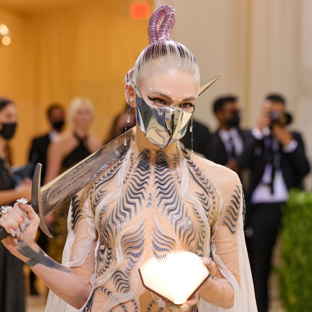 Grimes in einem futuristischen Outfit mit Schwert und Buch auf der Met Gala 2021.