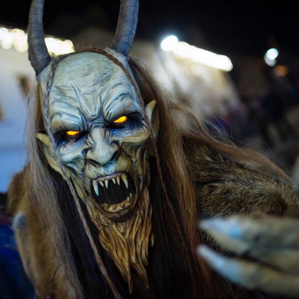 Ein Krampus mit Hörnern, Fell und einer furchteinflößenden Maske mit leuchtenden Augen.