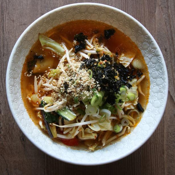 Eine Schüssel Ramen-Suppe mit Gemüse, Sprossen, Algen und Sesamkörnern.