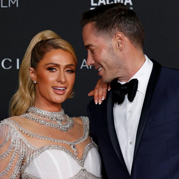 Paris Hilton posiert mit einem Mann im Smoking auf einer Veranstaltung.