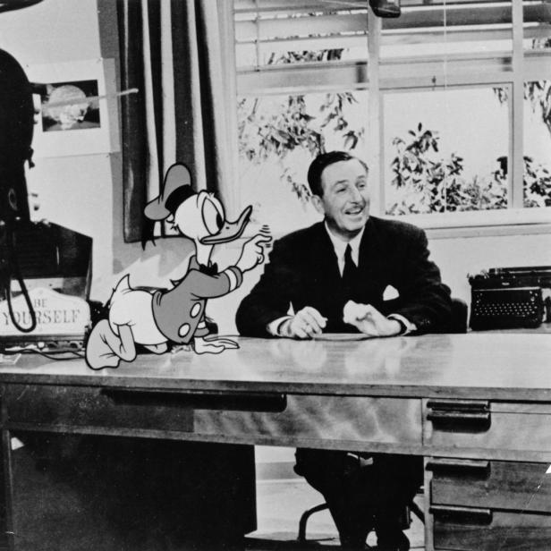 Walt Disney sitzt mit Donald Duck an einem Schreibtisch.