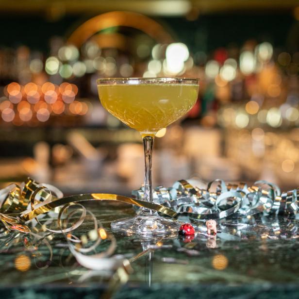 Ein „Old Cuban“-Cocktail steht auf einer Bar, dekoriert mit Partygirlanden.