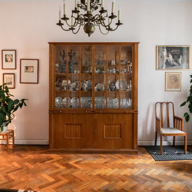 Ein Wohnzimmer mit einem großen Holzschrank, antiken Möbeln und Parkettboden.