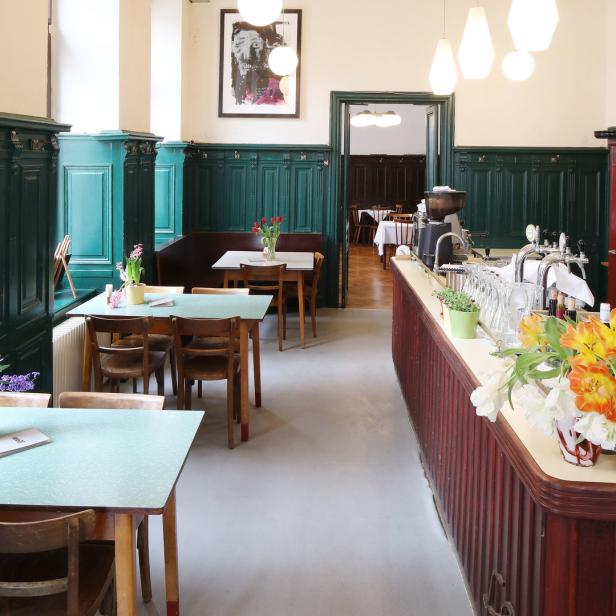 Innenansicht eines traditionellen Wiener Kaffeehauses mit Tischen, Stühlen und einer Bar.