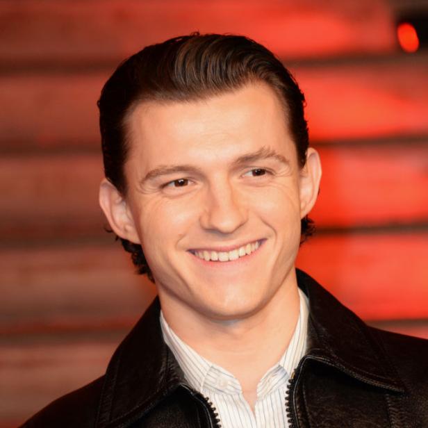 Tom Holland lächelt in einer schwarzen Lederjacke.