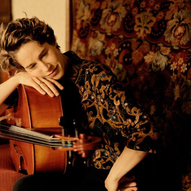 Eine Frau lehnt mit geschlossenen Augen an einem Cello.
