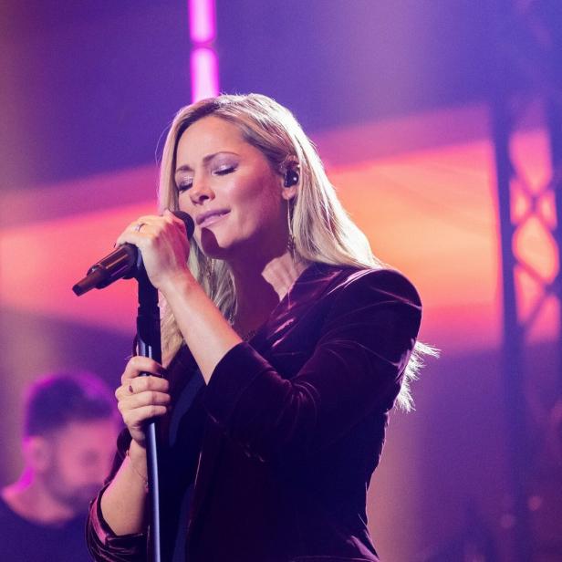 Helene Fischer singt auf einer Bühne in ein Mikrofon.