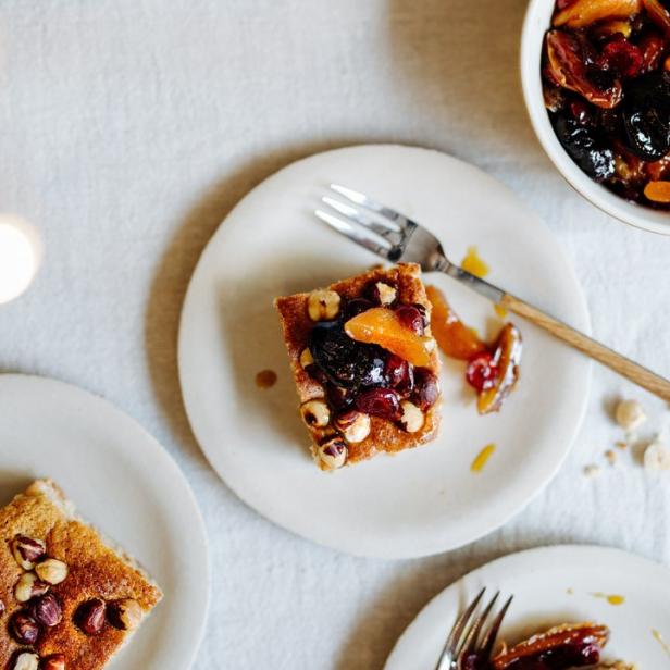 Drei Teller mit Kuchenstücken, garniert mit Nüssen und Trockenfrüchten, stehen auf einem Tisch.