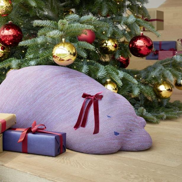 Ein Weihnachtsbaum mit goldenen und roten Kugeln, umgeben von Geschenken und einem lila Kissen.