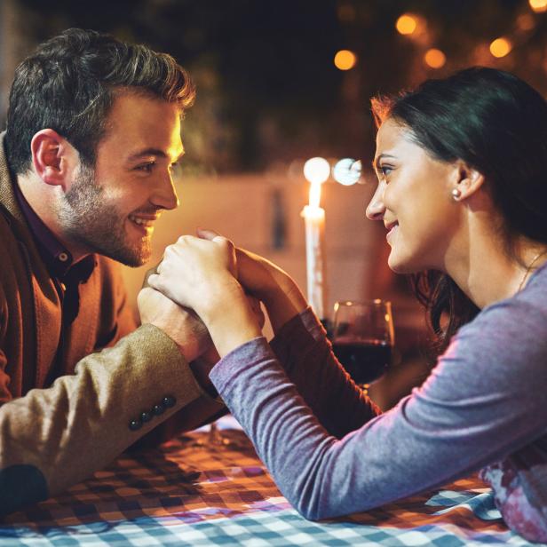 Ein Paar hält Händchen bei einem romantischen Abendessen mit Kerzenlicht.