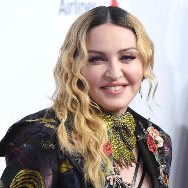 Ein Porträt von Madonna mit blonden Locken und einem verzierten Blazer.