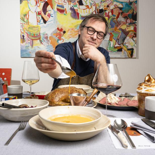 Ein Mann gießt Soße über eine Mahlzeit mit Suppe, Braten und Dessert.