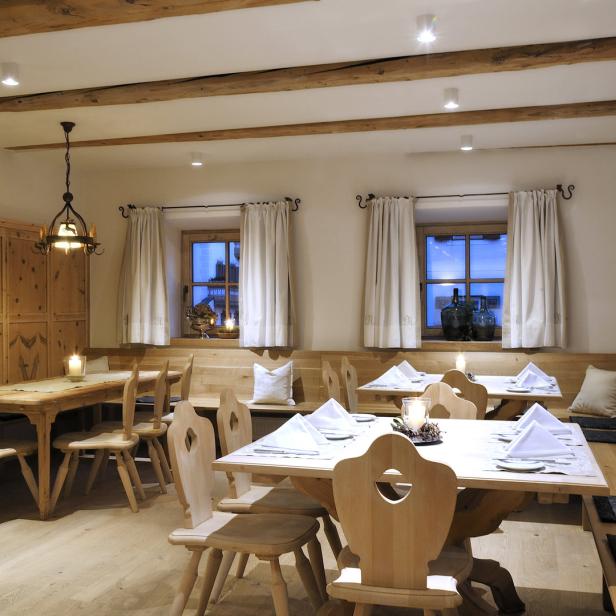 Einladender Speisesaal mit Holztischen und Stühlen, gedeckt mit weißen Servietten.