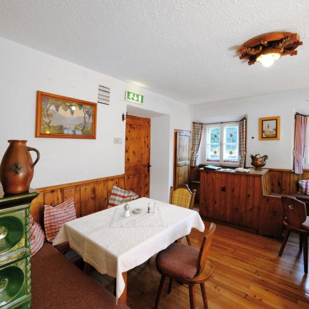 Ein traditionell eingerichtetes Esszimmer mit Kachelofen und Holztäfelung.