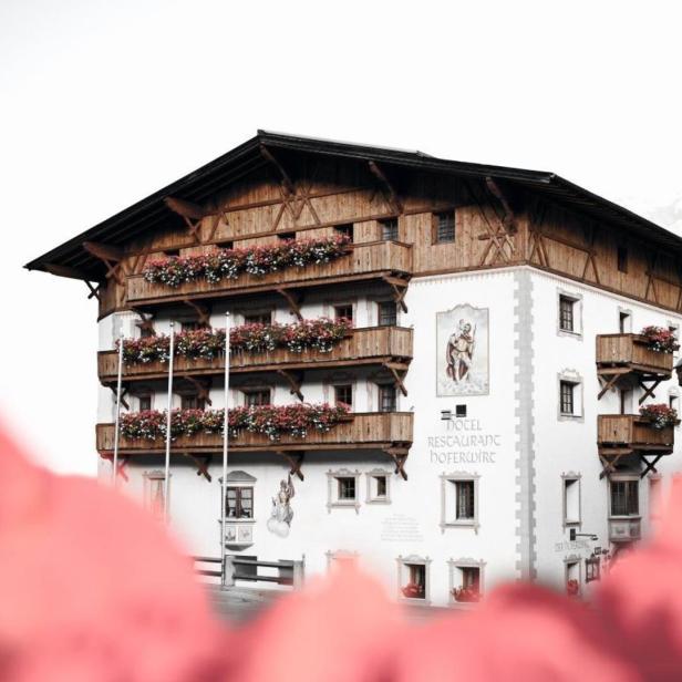 Das Hotel Restaurant Hoferwirt mit blumengeschmückten Balkonen in den Alpen.