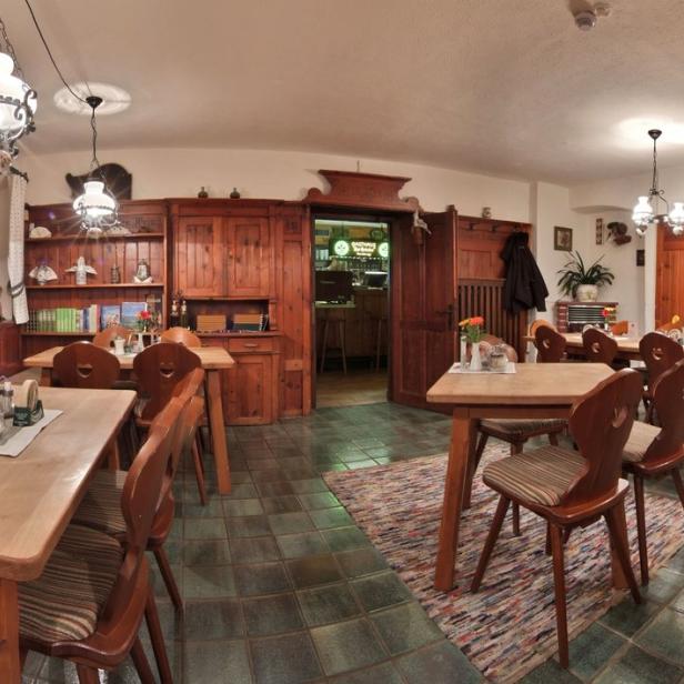 Panoramaaufnahme eines traditionellen bayerischen Gasthauses mit Holztischen und Stühlen.