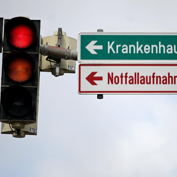 Rote Ampel, daneben Schilder mit Aufschrift "Krankenhaus" und "Notaufnahme"