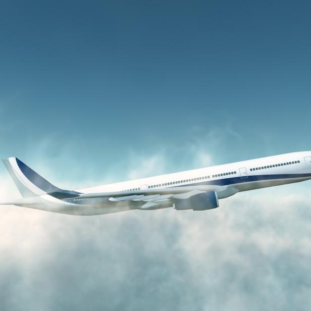 Ein weißes Passagierflugzeug fliegt über den Wolken.