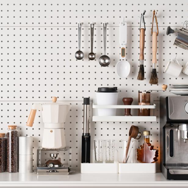 Eine Kaffeestation mit Espressomaschine, Mokka-Kanne und Zubehör vor einer Lochwand.