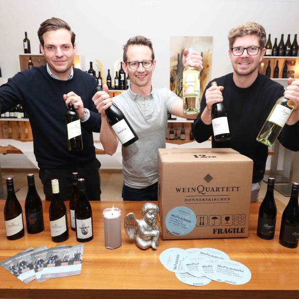 Drei Männer präsentieren Weinflaschen der Marke „Wein Quartett Donnerskirchen“.