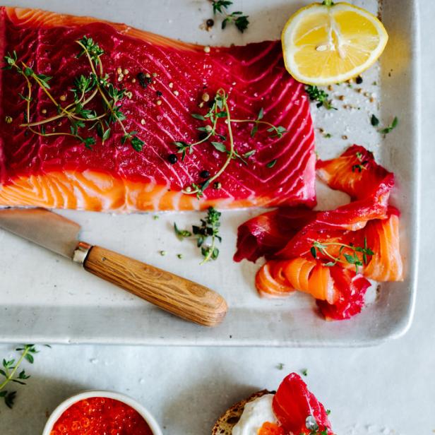 Ein Stück Lachs, Lachsscheiben und Lachsbrote mit Kaviar und Zitrone auf einem Tisch.